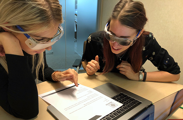 Image of two women wearing goggles that simulate visual impairments